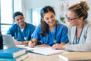 Nursing student working with academic mentors, reviewing notes and smiling after achieving success. Nursing Assignment help in uk